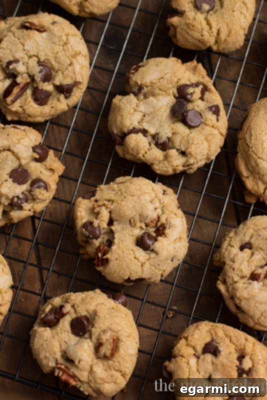 Freshly baked brown butter pecan chocolate chip cookies cooling on a wire rack, steam gently rising.