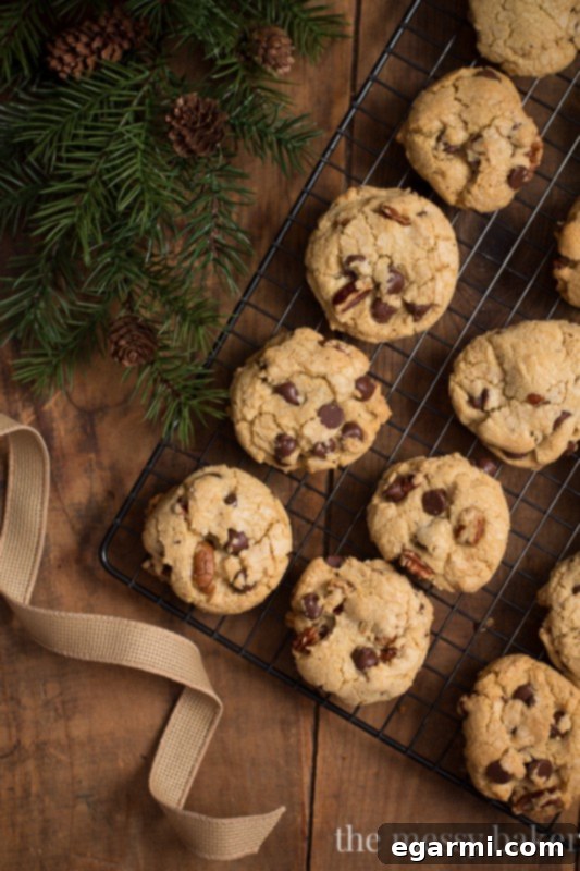Raw scoops of brown butter pecan chocolate chip cookie dough arranged on a parchment-lined baking sheet, ready for the oven.