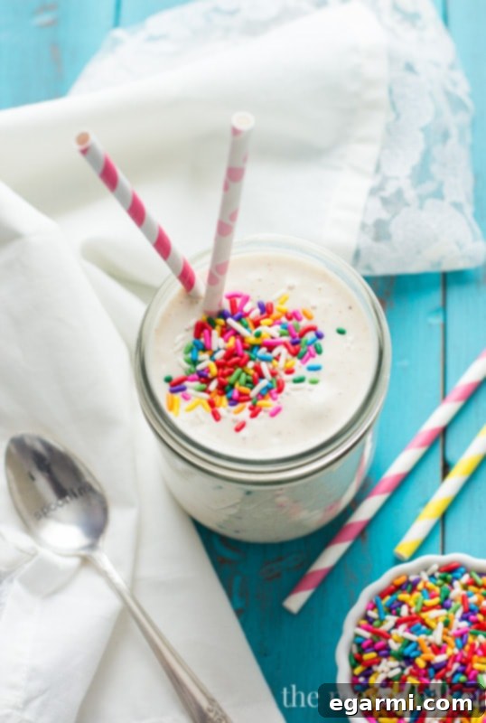 A beautifully presented Healthy Funfetti Shake in a clear glass, showing off the colorful sprinkles and creamy texture.