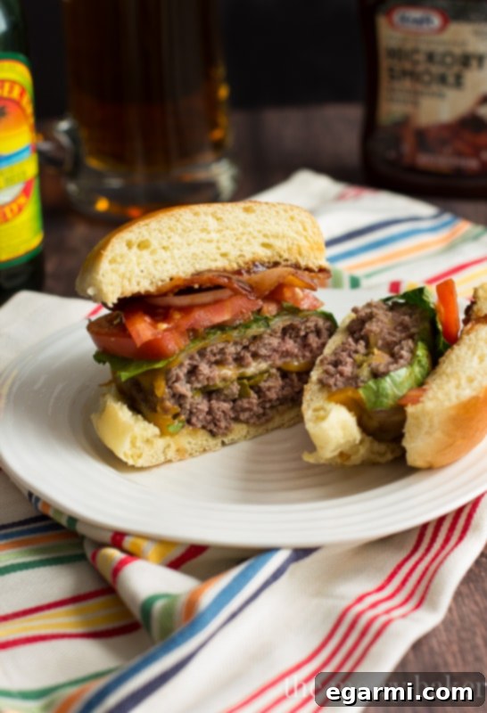 Jalapeño Popper Stuffed Bacon Burgers - A close-up of a burger cut in half, showing the melted cheese and jalapeños inside.