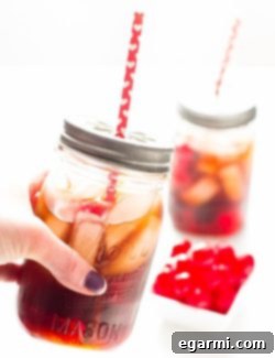 A glass of Black Cherry Cuba Libre cocktail with cherries and ice.