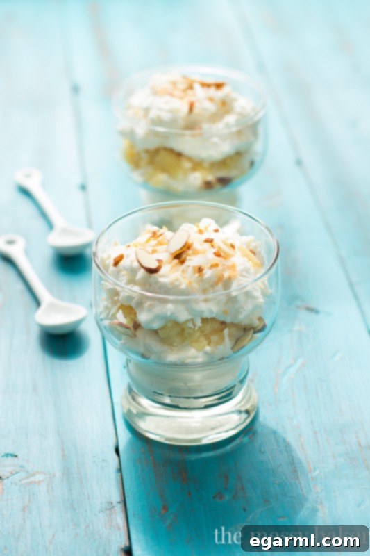 Close-up of a serving of Pina Colada Fool showing beautiful layers of whipped cream and pineapple with toasted coconut.