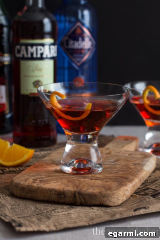 Classic Negroni Cocktail | A hand stirring a Negroni in a mixing glass with a bar spoon.