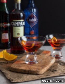 Classic Negroni Cocktail in a rocks glass with a large ice cube and an orange peel garnish.