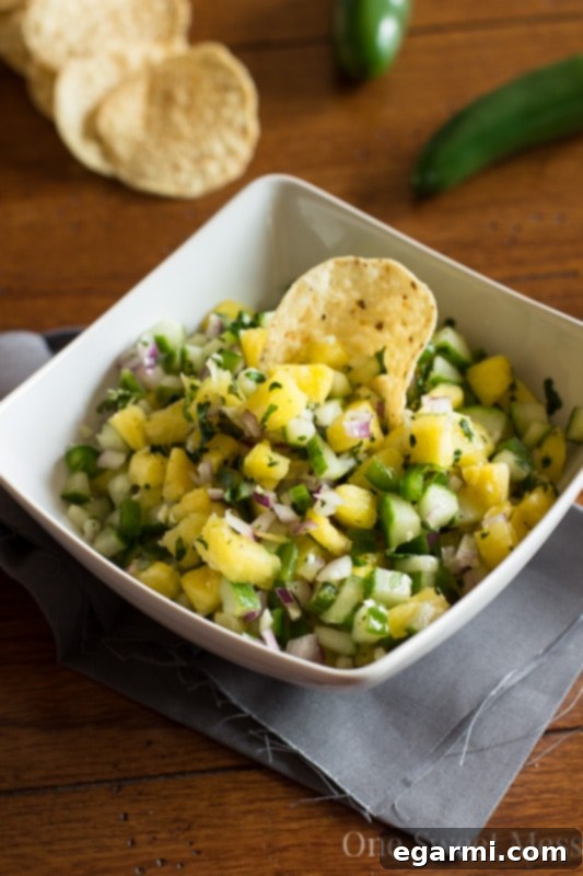 A bowl of Pineapple Cucumber Salsa with a serving spoon, ready to be enjoyed