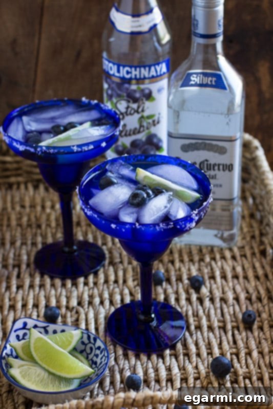 Pitcher of Blueberry Margaritas with glasses and garnishes