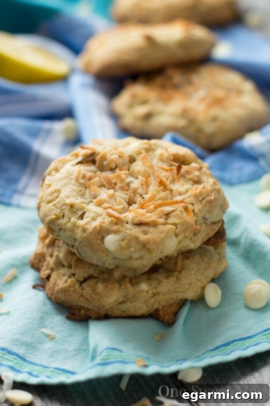 A hand holding a Soft-Baked Lemon Coconut Cookie, showcasing its texture and golden edges.