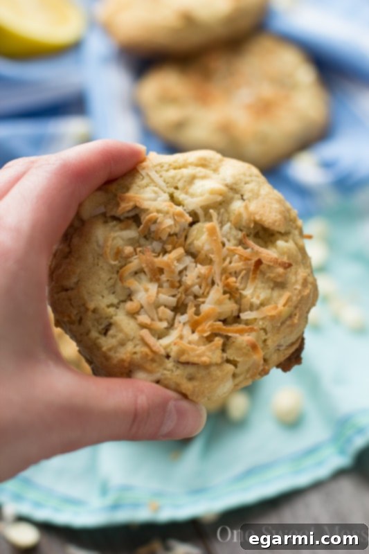 Soft-Baked Lemon Coconut Cookies with toasted coconut on top, ready for a bite.