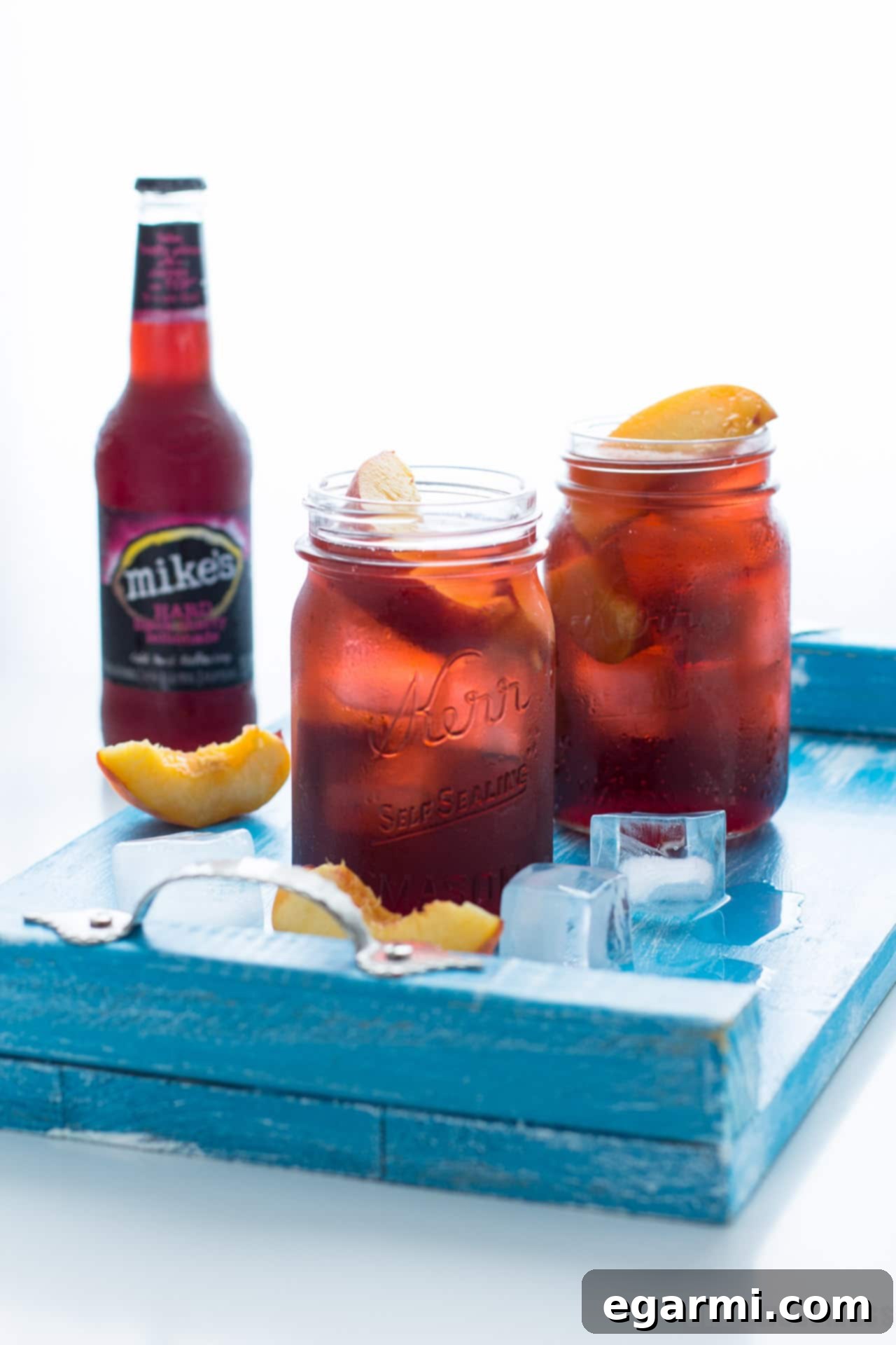 A vibrant Black Cherry Peach Smash cocktail, garnished with fresh peach slices, served in a tall glass with ice, perfect for summer.