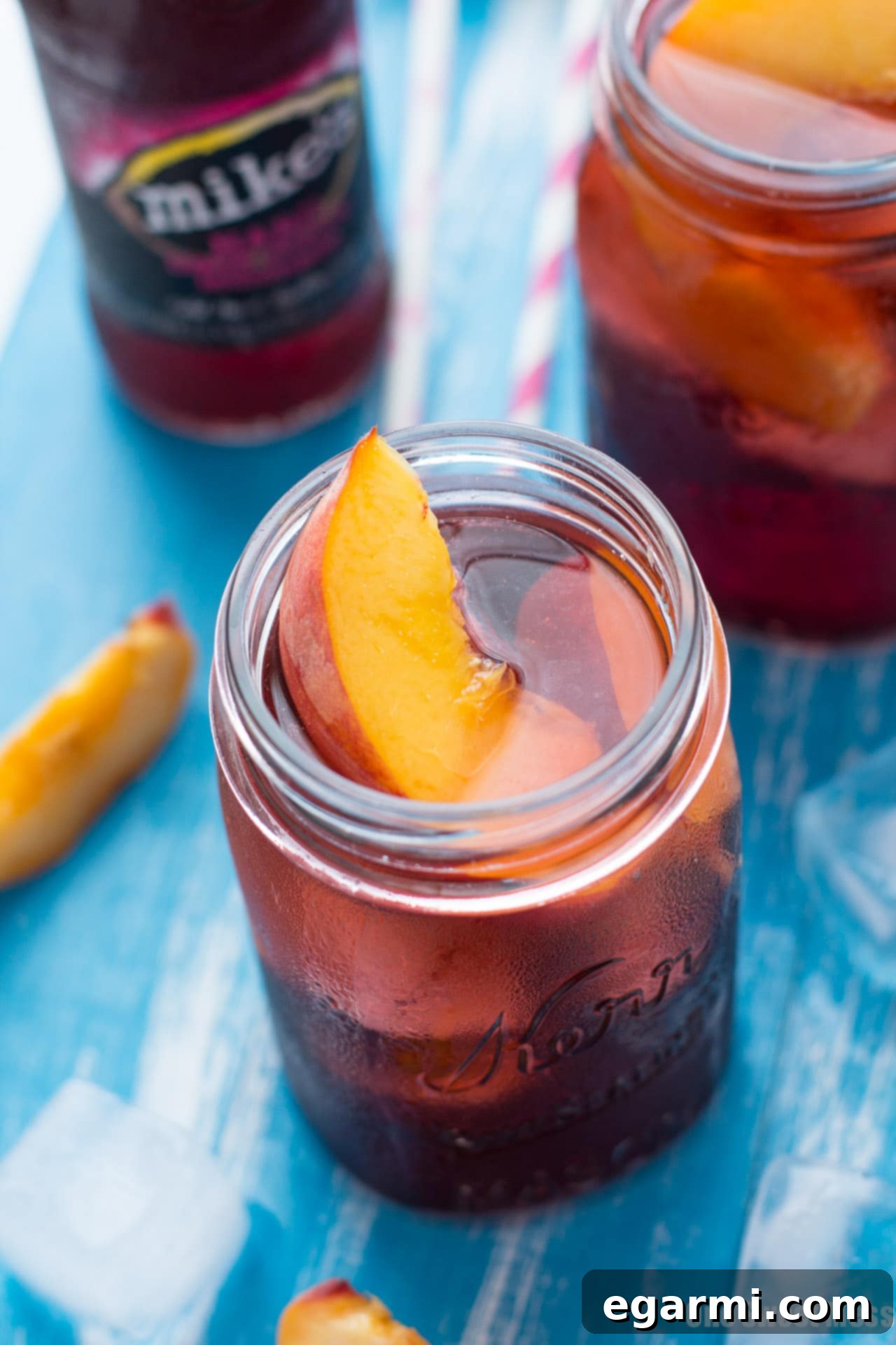 A close-up of a Black Cherry Peach Smash, showing the deep red color and peach slices, ready to be enjoyed on a sunny day.