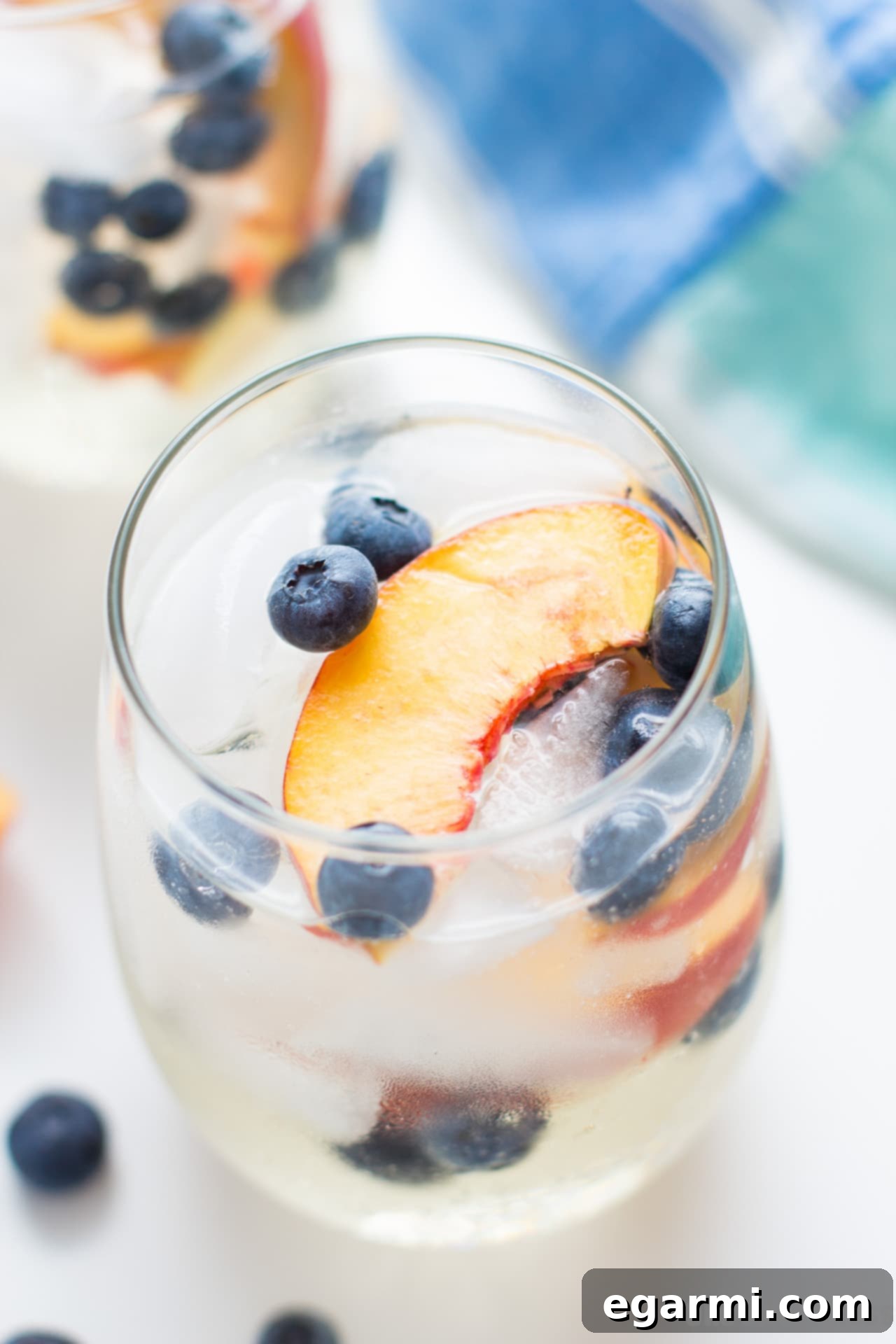 Blueberry Peach Sangria being stirred in a pitcher with a wooden spoon
