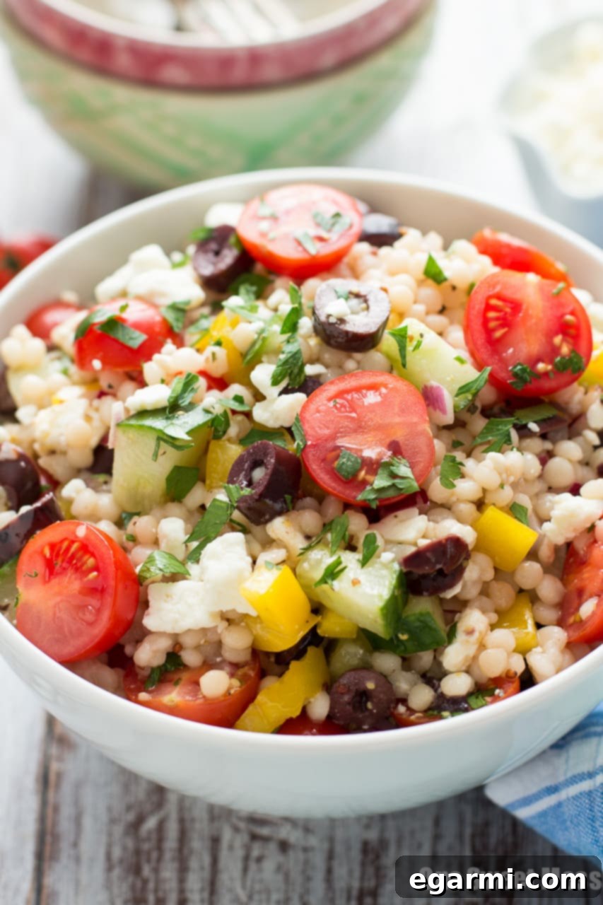 Ingredients for Greek Israeli Couscous Salad being mixed in a large bowl