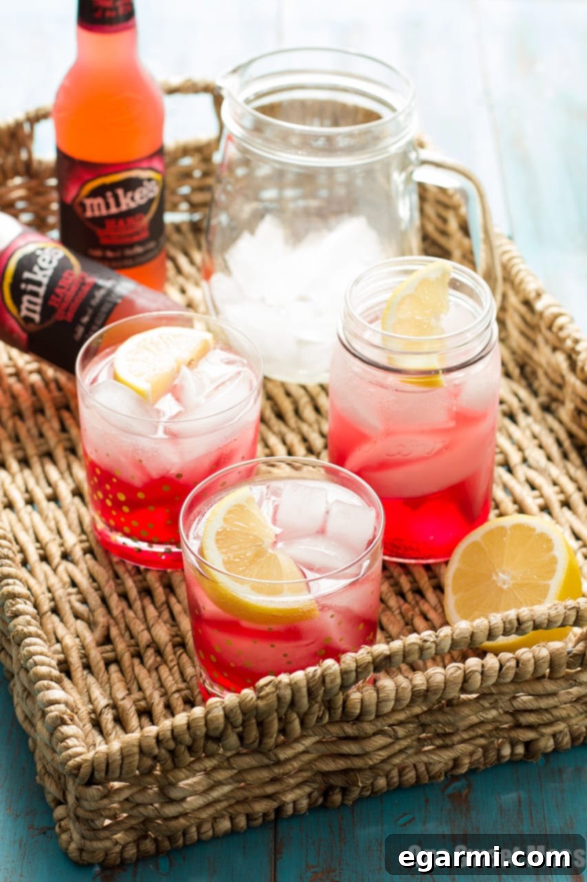 A refreshing Cran-Apple Splash cocktail, featuring Mike's Hard Cranberry Lemonade, apple cider, and apple-infused whiskey, served over ice with apple slices for garnish.