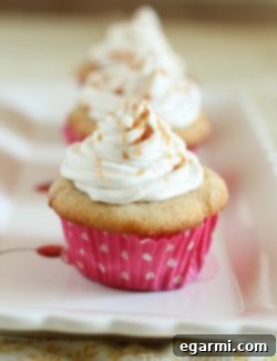 A perfectly baked Caramel Stuffed Snickerdoodle Cupcake with a swirl of frosting.