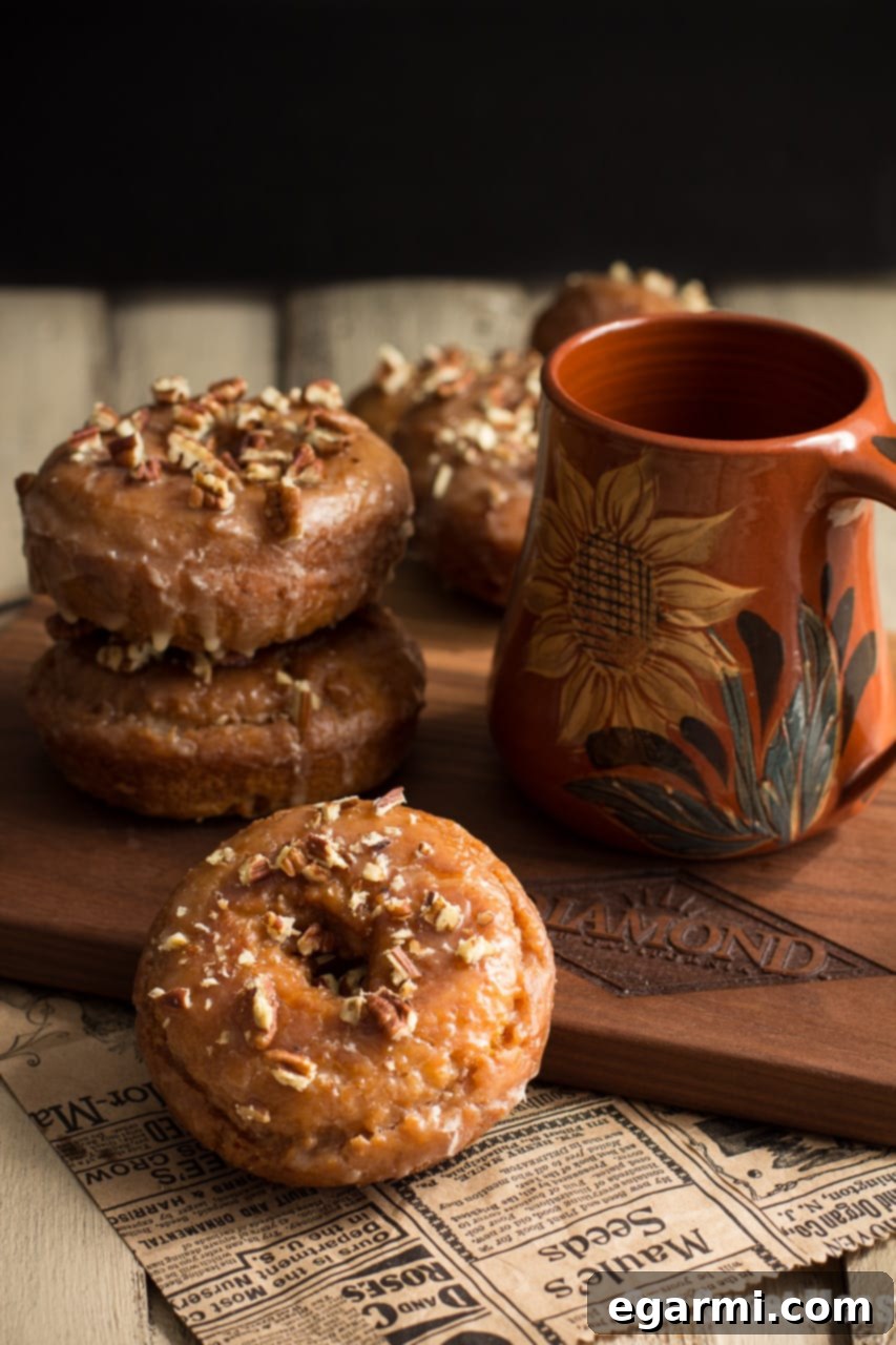 Delicious Pumpkin Spice Donuts with Maple Glaze on a wire rack, ready to be enjoyed.