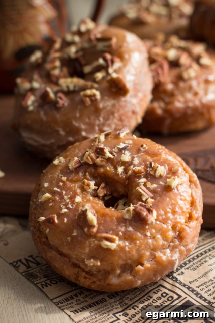 Close-up of a stack of Pumpkin Spice Donuts with Maple Glaze, showing the texture and pecan topping.