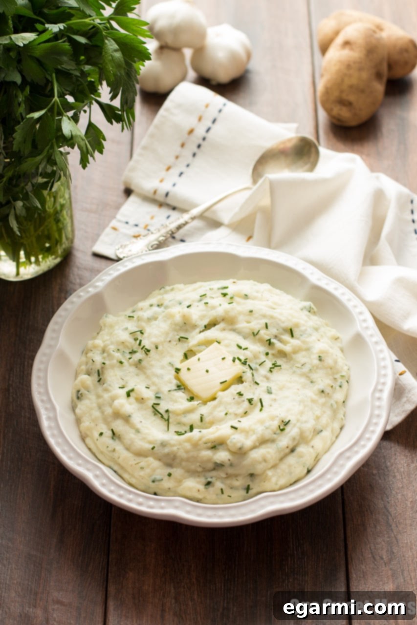Close up of hands mashing cooked potatoes in a pot, demonstrating creamy texture