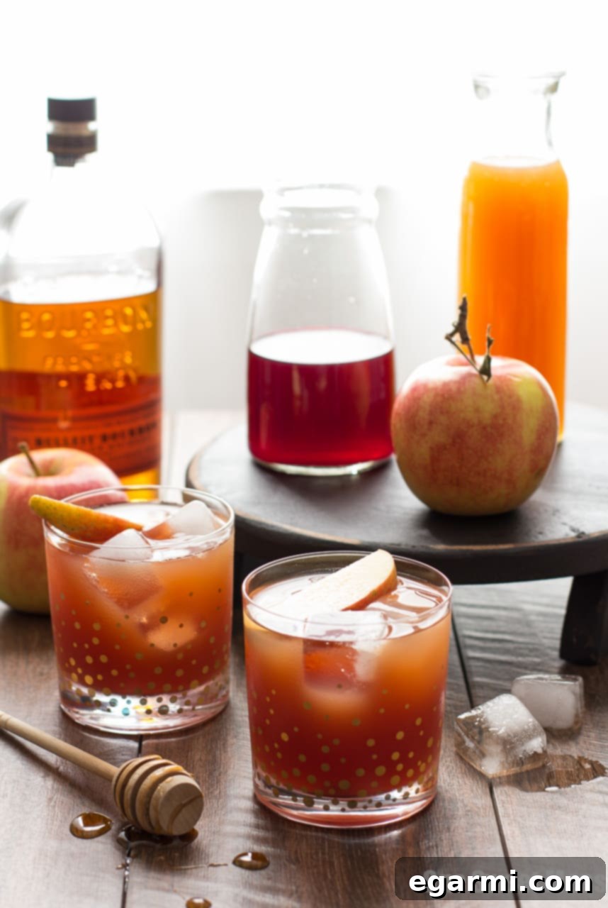 Two glasses of Pomegranate Cider Bourbon Splash on a wooden surface