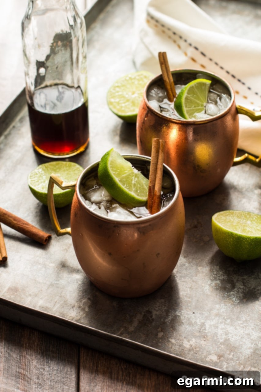 The Mid-Winter Mule: A comforting bourbon cocktail featuring Pimm's No.1, spicy ginger beer, and homemade cinnamon simple syrup, served in a classic copper mug.