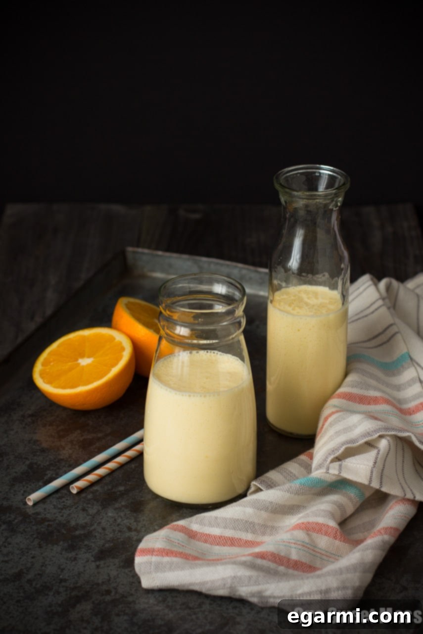 Close-up of a thick, creamy Dreamsicle Smoothie in a glass, with orange slices and a straw, emphasizing its rich texture and inviting appearance.